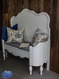 a white bench with pillows on it in front of a wooden wall and wood paneling