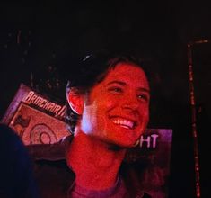 a young man smiling in front of a red light