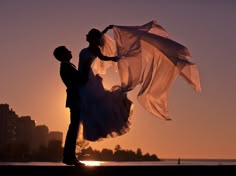 the bride and groom are holding their veils at sunset