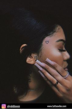 a woman holding her face to her ear with the word love tattooed on it's side