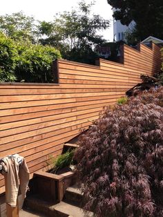 a wooden fence next to some bushes and trees