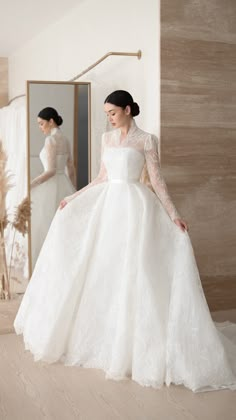 a woman in a white wedding dress standing next to a mirror