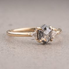 an engagement ring with three stones on the side and one stone in the middle, sitting on a gray surface