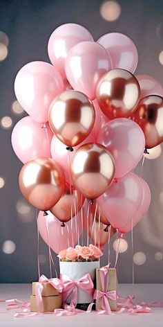 a bunch of balloons are in the air with pink ribbons and bows around them on a table