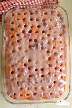 a casserole dish filled with fruit and cream sauce on top of a checkered cloth