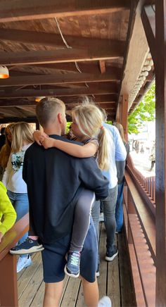 two people hug each other while standing on a wooden platform in front of some people