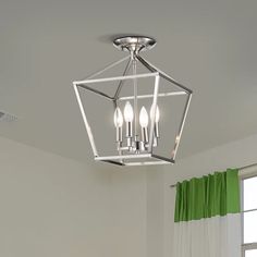 a light fixture hanging from the ceiling over a bed in a room with green curtains