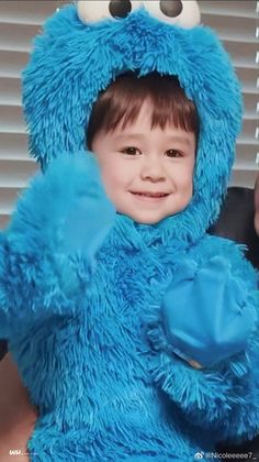 a little boy dressed in a cookie monster costume with his hand up to the camera