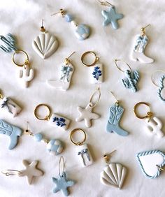 many different types of key chains on a white sheet with blue and white ornaments hanging from them