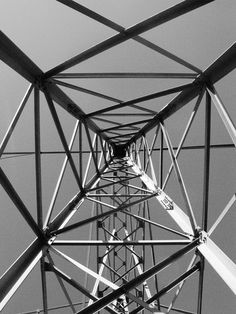 black and white photograph of the top of an electrical tower with wires running through it