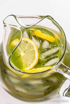 a pitcher filled with green liquid and lemon slices