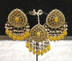 Elevate your style with this stunning Yellow Pearl Long Chandbali Earring and Tikka Set. The elegant jewellery set is crafted with precision and features a beautiful gold main stone colour. The set is perfect for women who want to add a touch of ethnic charm to their wardrobe. The set is made in India and boasts an East Indian ethnic and regional style. It is a perfect addition to your jewellery collection and can be worn on any occasion. The set includes a long chandbali earring and a tikka, both adorned with beautiful yellow pearls. Add a touch of luxury to your outfit with this gorgeous jewellery set. Unique Wedding Earrings, Elegant Jewellery, Yellow Pearl, Chandbali Earrings, Stone Colour, South Indian Jewelry, Wedding Jewelry Earrings, Jewellery Set, Gorgeous Jewelry