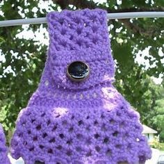 a purple crocheted scarf hanging on a clothes line with trees in the background