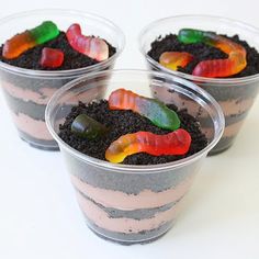 three plastic cups filled with dirt and gummy bears on top of each other,