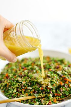 someone pouring dressing into a white bowl filled with vegetables