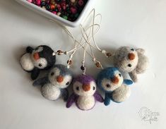 four small stuffed animals are hanging from strings next to a bowl with beads on it