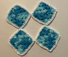 four crocheted squares are arranged on a table