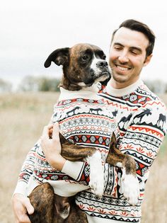 a man holding a dog in his arms while wearing an ugly sweater and smiling at the camera