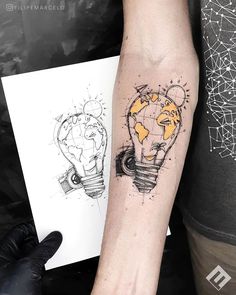 a person with a tattoo on their arm holding a piece of paper and a light bulb