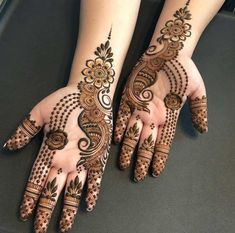 two hands with henna tattoos on their palms and arms, both showing intricate designs