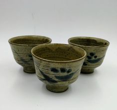 three ceramic bowls sitting side by side on a white surface with blue speckles