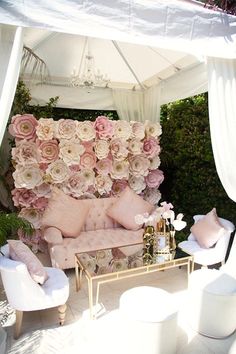 an outdoor area with white furniture and pink flowers on the wall behind it, as well as a large teddy bear