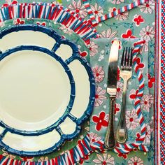 an empty plate and silverware on a colorful table cloth with red, white and blue flowers