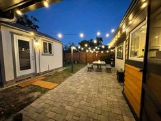 an outdoor patio with lights strung over it and a picnic table in the foreground