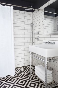 a white bathroom with black and white tile flooring, shower curtain, and sink