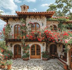 a stone house with red flowers on the balcony