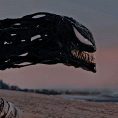 a person laying on the ground with a large monster head in front of their face