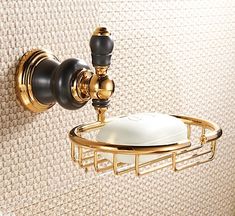 a gold and black toilet paper holder with a white pillow on it's side