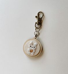 a keychain with a small embroidered cat on it's front and back