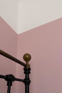 a pink and white room with a black iron bed frame in front of the wall