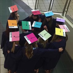 a group of girls in graduation gowns with colorful sticky notes attached to their heads