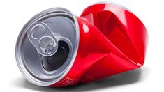 an empty red soda can sitting on top of a white surface with the lid open