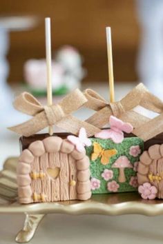 the cake is decorated with pink flowers and green icing, along with two little fairy houses