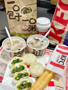 two cups of soup with chopsticks and other food items on a table next to paper bags