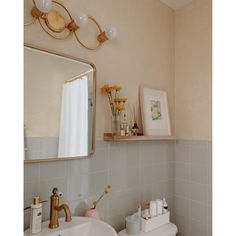 a bathroom with a sink, mirror and toiletries on the shelf above the sink