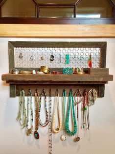 a wooden shelf filled with lots of necklaces and bracelets hanging from it's sides