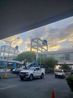 several cars parked in a parking lot under a cloudy blue and white sky at an airport