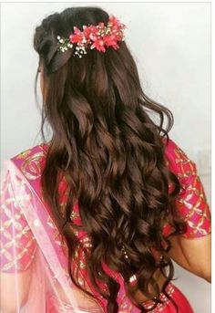 a woman with long dark hair wearing a pink sari and a flower headpiece