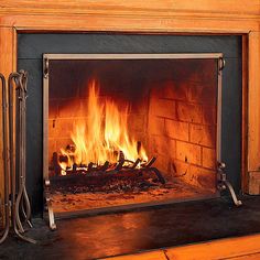 a fire burning in a fireplace next to a wooden mantle with iron bars on the sides