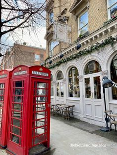 two red telephone booths sitting in front of a building