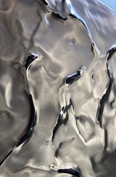 an abstract metal surface with black and white lines on it, as well as water