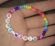 a woman's hand holding a colorful beaded bracelet with the word hope on it