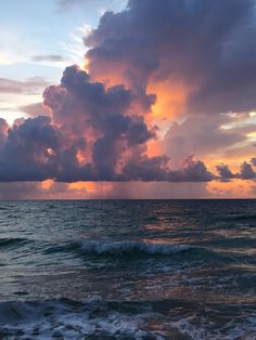 the sun is setting over the ocean with clouds in the sky