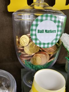 a glass jar filled with lots of gold coins and some paper on top of it