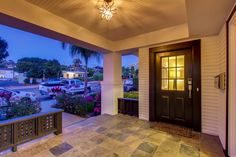 the front porch is lit up at night with flowers and cars parked in the driveway