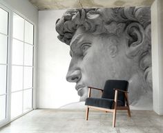 a chair sitting in front of a wall with a statue on it's side